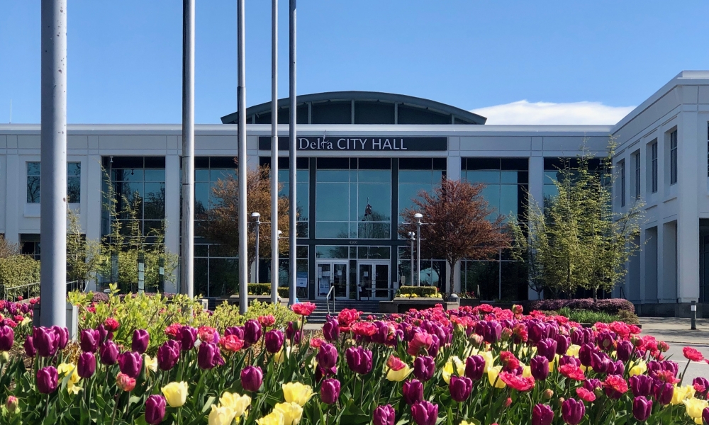 Delta city hall with flowers in bloom in front of the building