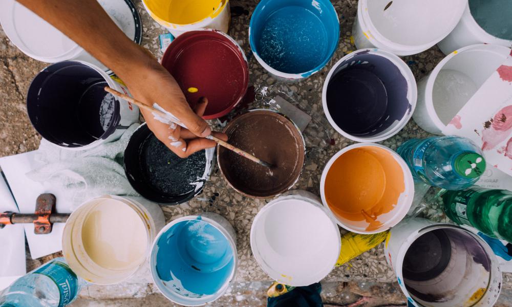 hand dipping paintbrush into paint can