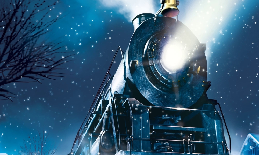 A small boy stands outside in the middle of the night in just his night gown, in front of the titular Polar Express: a huge steam engine train with a penetrating white light emerging from its front.