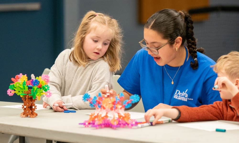 Children work with a volunteer to build a toy at a community recreation program.