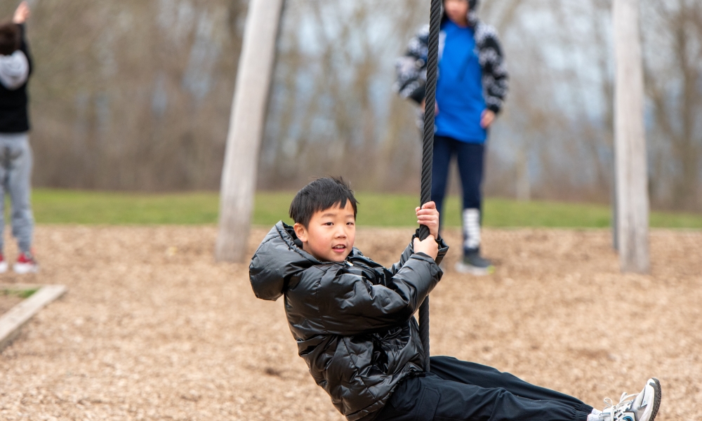 Camper slides along zipline swing at day camps.