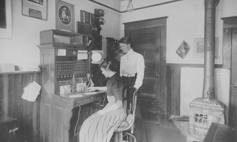 Two people use a telephone in early Delta's history.