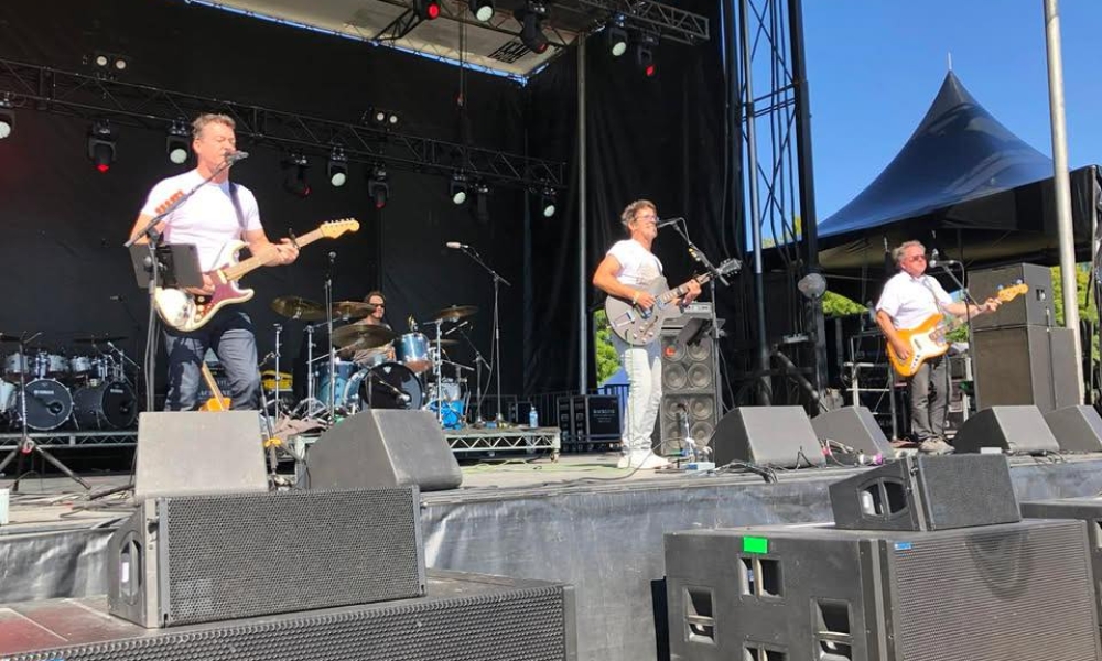 All the Kings Ment perform rock music on an outdoor stage. 