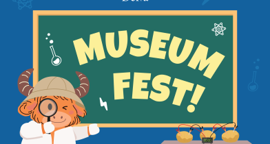 The Yak stands in front of a chalk boards that says MUSEUM FEST on it. 