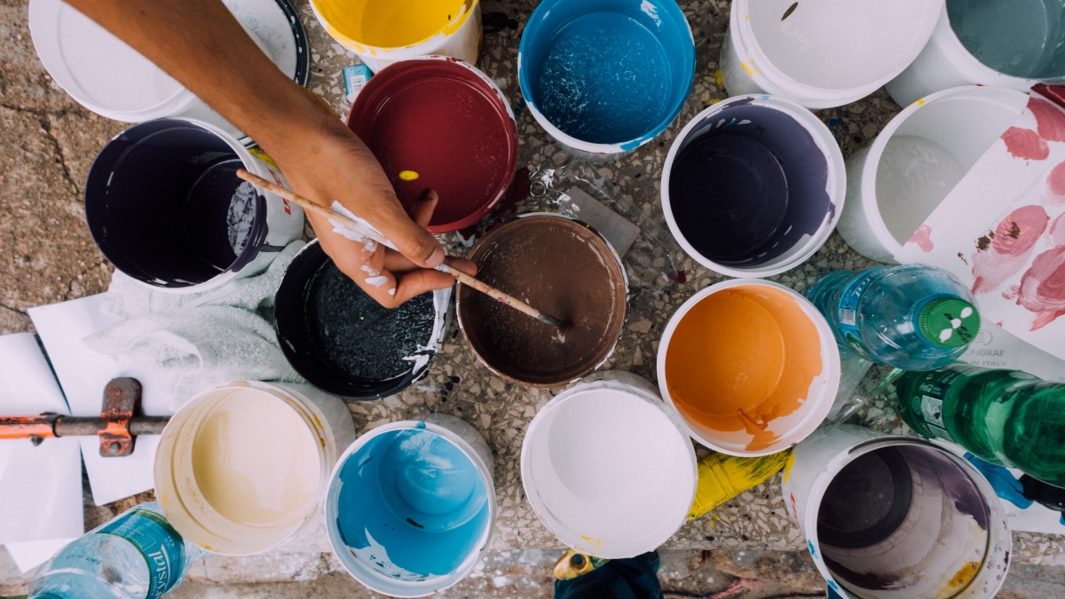 hand dipping paintbrush into paint can