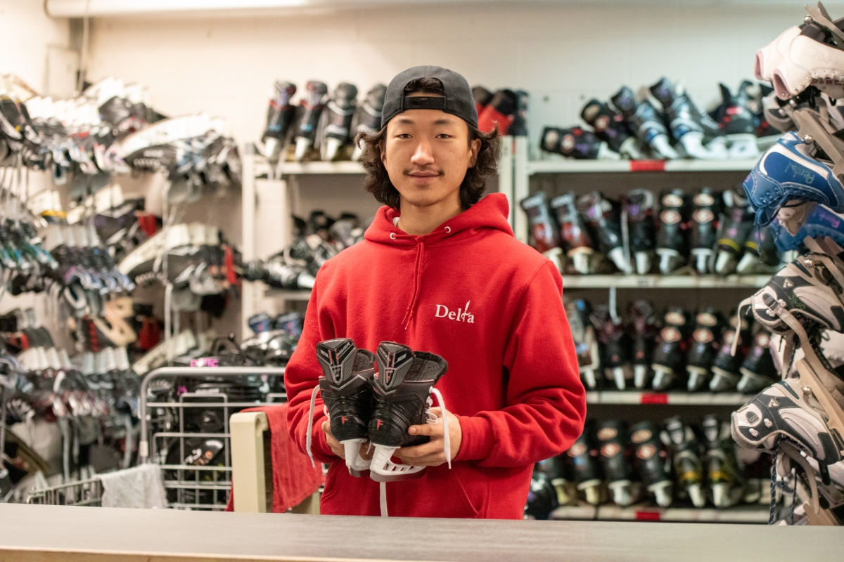 A Delta staff member hands a pair of skates from behind the rental counter.