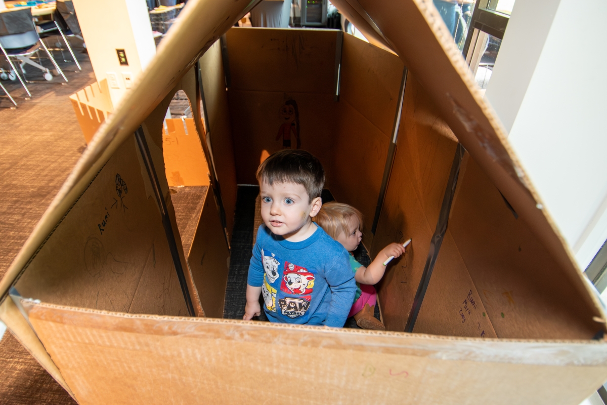 A visitor hangs out in a cardboard fort.