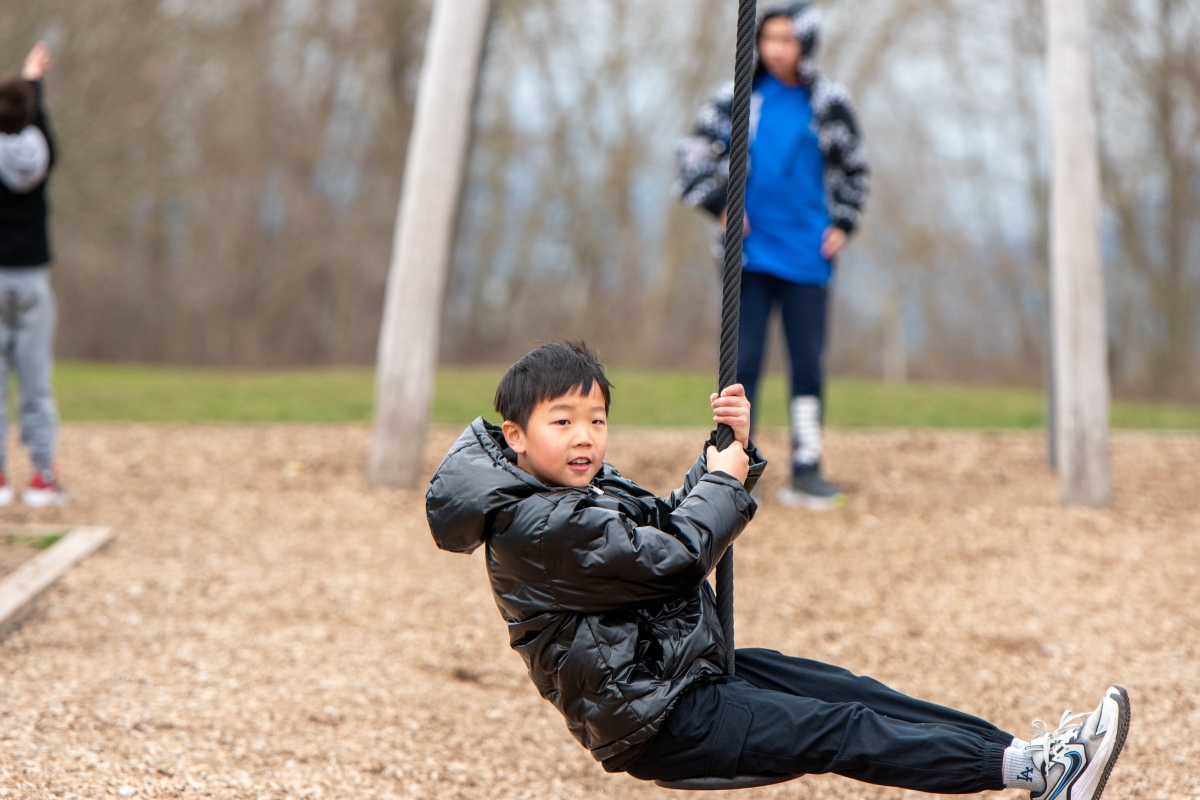 Camper slides along zipline swing at day camps.