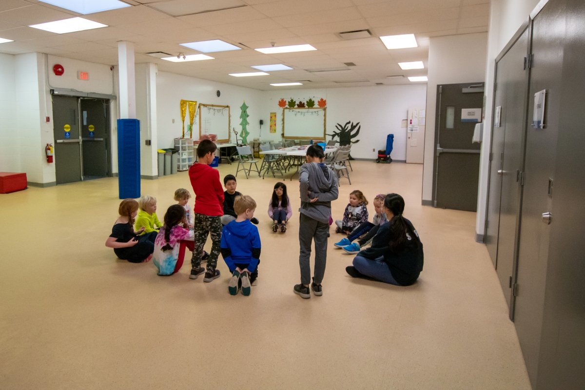 Kids sit in a circle as they play a game at day camps!