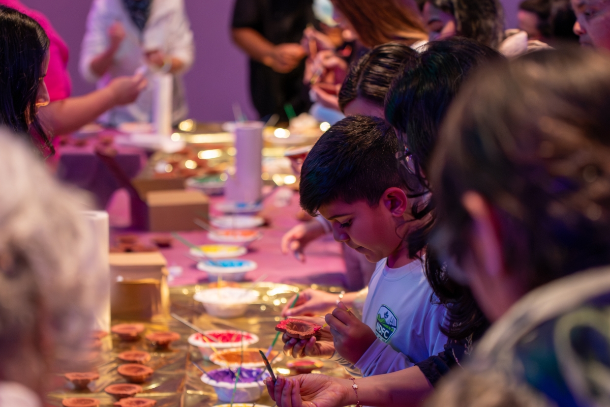 children decorating diyas with paint at a table