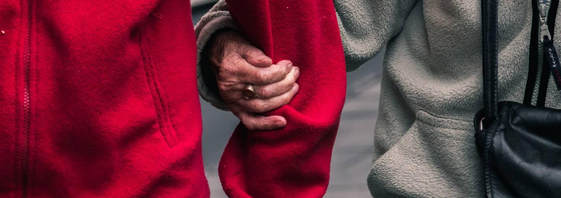 hand holding onto elbow in red jacket
