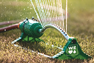 green sprinkler on grass spraying water