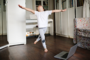 Kid jumping with arms outstretched in a living room