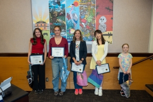 The winners of the 2026 Banner Contest stand in front of their designs. 