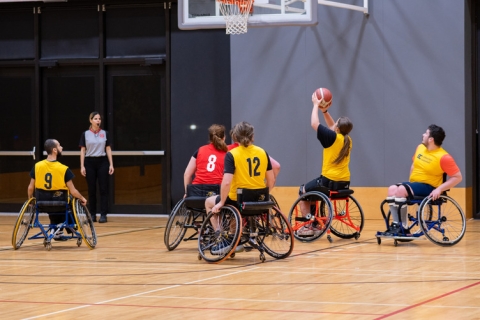 A group of young people playing basketball while using wheelchairs.