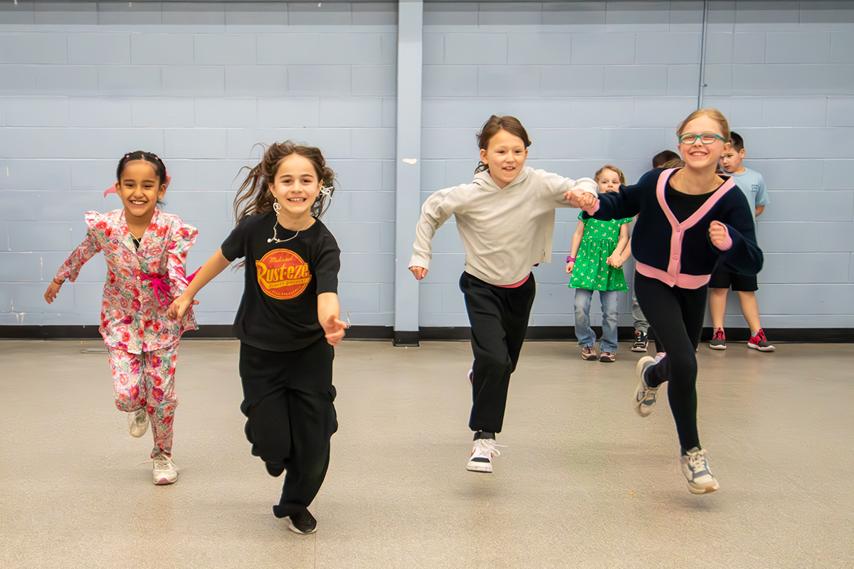 Four girls run excitedly during a Winter Break Camp.