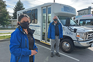 Woman and man wearing face masks stand in front of vaccine bus